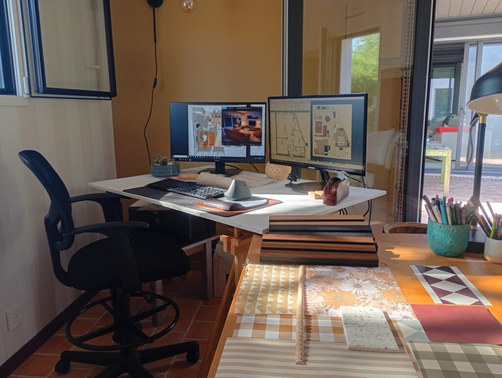 Bureau de décoratrice d'intérieur avec double écran, plans 3D et échantillons de matériaux